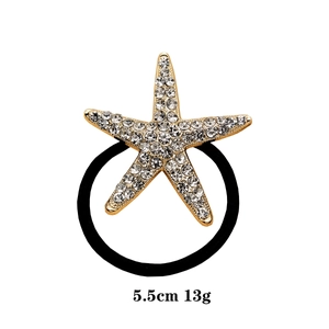Detail of gold starfish hair tie with sparkling rhinestones and 5.5cm diameter specs