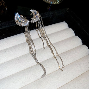 Macro shot of silver crescent moon earrings with long tassels and blue accents