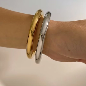 Minimalist polished stainless steel bangles in gold and silver finish worn on wrist
