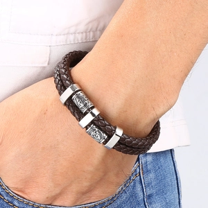Détail du bracelet en cuir tressé marron foncé avec perles gravées sur poignet masculin
