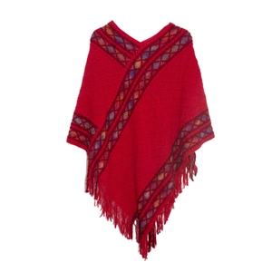 Detail of red knit poncho with V-neck, geometric ethnic trim and fringe tassel hem