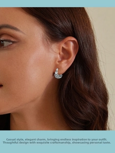 Close-up of vintage hollow pattern sterling silver hoop earrings worn on female ear