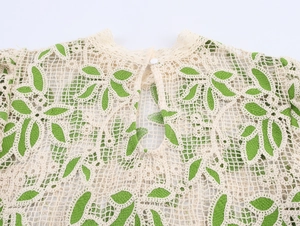 Détail du tissu en dentelle crochetée avec motif de feuilles et fermeture boutonnée