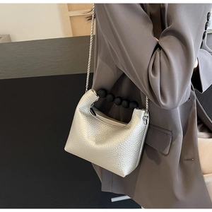 Silver textured crossbody bag with black spherical handle and silver chain strap details