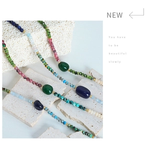 Detailed close-up of handmade natural stone necklace with multi-colored agate beads on rock