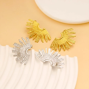 Detailed view of fan-shaped hammered gold and silver earrings on a minimalist pedestal