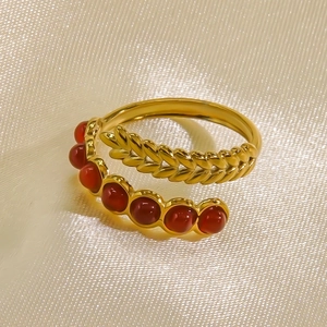 Anello aperto in acciaio dorato con 7 gemme rosse e dettaglio texture spiga di grano