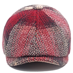 Detail of red and black herringbone wool newsboy cap with vintage texture and top button