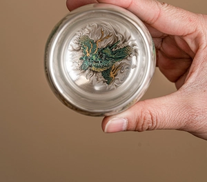 Macro top view of a ceramic tea cup featuring an intricate green and gold dragon motif