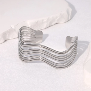 Detailed view of silver wavy minimalist stainless steel open bangle on white stone