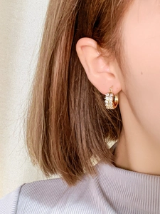 Nahaufnahme der goldenen Creolen mit zwei Reihen klarer Zirkonia am Ohr des Models
