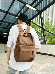 Rear view of brown canvas backpack on model featuring thick straps for daily commute