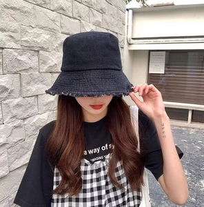 Photo de rue d'un chapeau bob en denim noir avec bords effilochés et détails