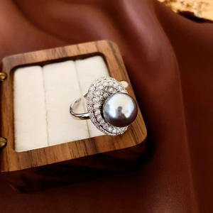 Detail view of silver oval ring with grey pearl and pavé accents in a wooden jewelry box