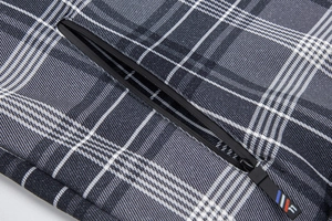 Makro-Detail der karierten Jacke mit verdeckter Reißverschlusstasche und nummeriertem Tag