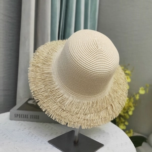 Detailed close-up of straw sun hat with bohemian fringe edge on a display stand