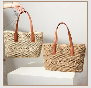 Detail of woven straw tote bags in beige and camel with brown PU leather handles