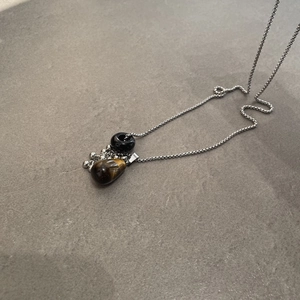 Detailed close-up of a vintage tiger eye stone teardrop pendant on a silver box chain necklace.