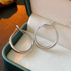 Créoles géométriques en argent présentées dans un écrin à bijoux en velours vert foncé
