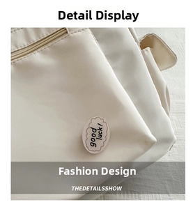 Detailed close-up of side zipper pocket with Good Luck patch on white canvas tote bag