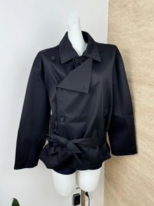Detail of black double-breasted short trench coat with adjustable collar and waist belt