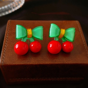 Boucles d'oreilles cerises avec nœuds verts et fruits rouges sur boîte en cuir