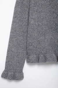 Close-up of gray knit cardigan featuring delicate ruffle trim and fuzzy wool texture