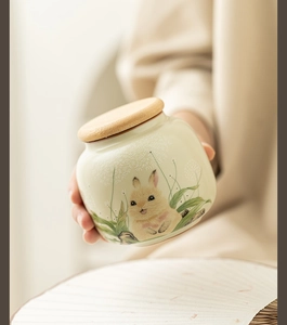 Close-up of hand-held Ru kiln rabbit ceramic tea canister with wooden lid and artistic rabbit art