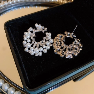 Vue macro de boucles d'oreilles géométriques argentées avec perles et strass sur velours