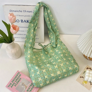 Detail of light green floral tote bag featuring a knotted shoulder strap and bow ribbon