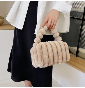 Close-up of beige plush handbag with soft pom-pom handle and fuzzy texture details
