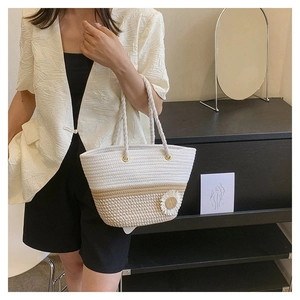 Model holding a floral woven tote bag with sunflower decoration in a chic indoor setting