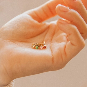 Detailed view of four colorful rhinestone stud earrings held in hand for size comparison
