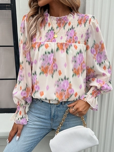 Detail of floral print blouse featuring smocked high neck and elastic cuffs for women