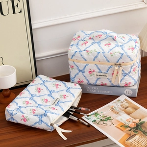 Detail of quilted makeup bag set with rose floral prints and blue ribbon zipper pulls