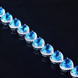 Luxurious heart-shaped blue sapphire bracelet with sparkling diamond halo on black background