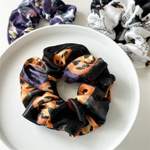 Detail of Halloween scrunchies with pumpkin, bat, and spider web prints on satin fabric