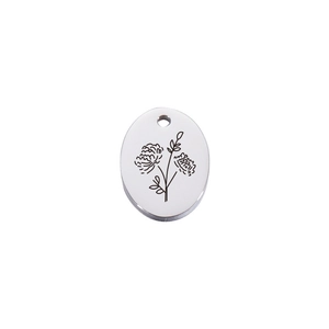 Macro shot of oval stainless steel pendant with etched flower and polished mirror finish