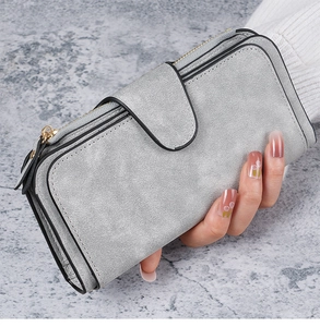 Close-up of a grey suede long wallet with snap buckle and zipper held by a model