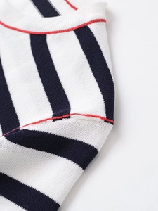 Detail of black and white striped knit fabric with elegant red trim and neat stitching