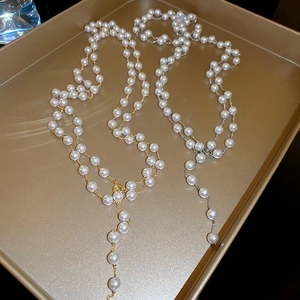 Détail de colliers en Y dorés et argentés avec perles posés sur un plateau doré