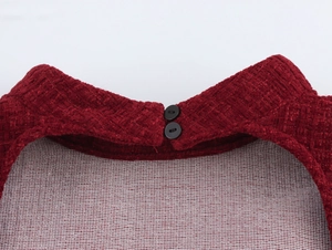 Gros plan du col en tweed rouge avec deux boutons ronds noirs et texture de tissu tissé