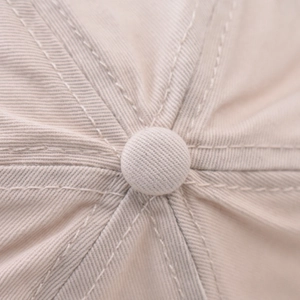 Close-up of top button and reinforced stitching on a cotton baseball cap