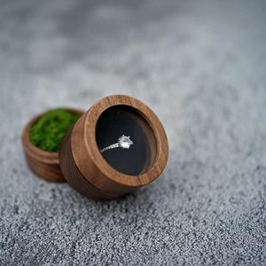 Close-up of walnut wood ring box with a glass window and a silver diamond ring inside