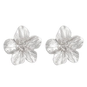 Macro detail of silver flower earrings with delicate petal texture and center stamen