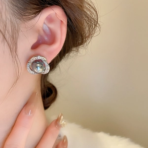 Détail d'une boucle d'oreille en perle grise avec spirale en zircon sur l'oreille