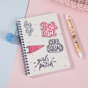 Primer plano de libreta de espiral blanca con tipografía artística de estilo pegatina