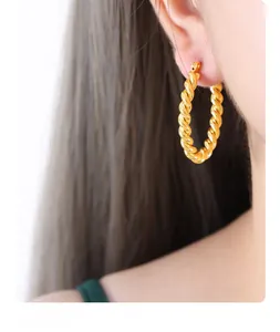 Close-up of a model wearing gold-plated 18k titanium steel hoop earrings with twist texture