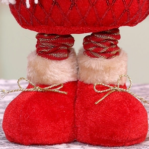 Detail of Christmas doll showing red velvet boots with gold bows and plush faux fur trim