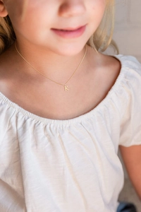 Close-up of golden letter K pendant necklace on model neck with minimalist jewelry style